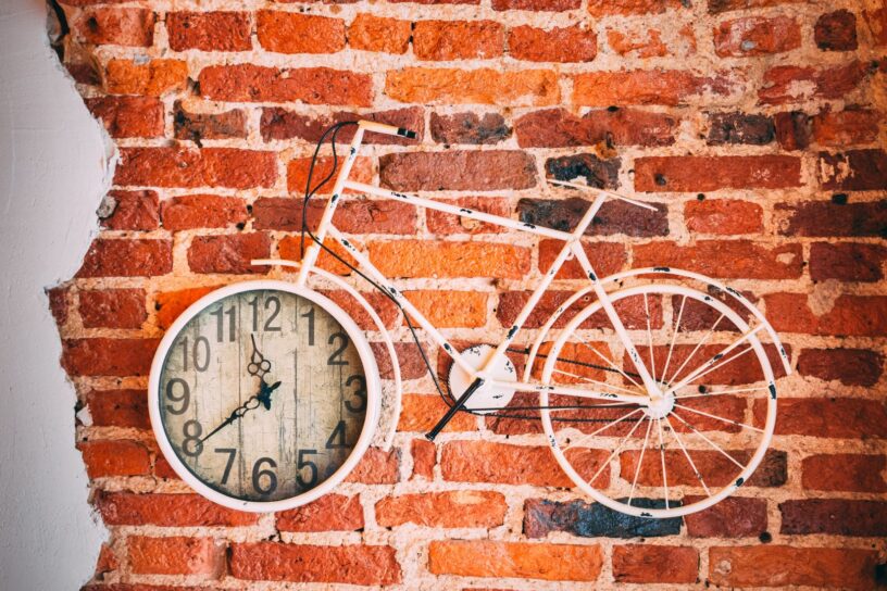 ściana z cegieł czerwona z zawieszonym rowerem z zegarem